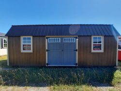 For sale 12x24 Lofted Barn Shed: A small shed with a metal roof and a black door is available at our store nearby.