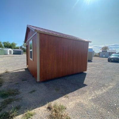 A small 14x14 Cabinette with a red roof available for sheds sale near me, located in a parking lot.