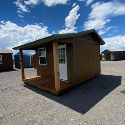 A 12x16 Cottage Shed for sale sitting in a parking lot.