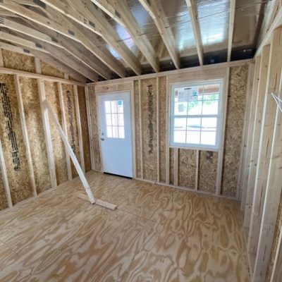 The inside of an unfinished room with wood framing, reminiscent of a 12x16 Cottage Shed.