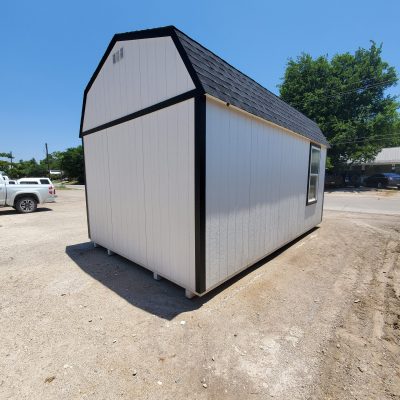 A white and black 12x20 Lofted Barn Shed for sale sitting on a dirt lot.