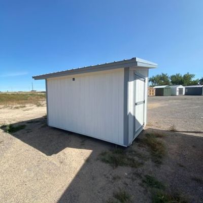 An 8x12 Studio Shed FOR SALE in a dirt lot.