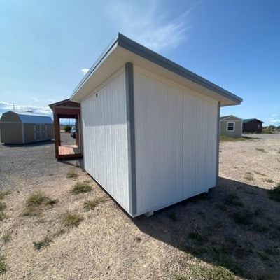An 8x12 Studio Shed sitting in a dirt lot, available for sale.