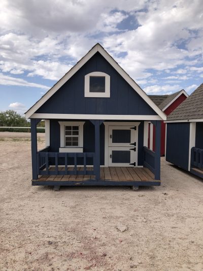 A small blue and white 8x12 Hideout Playhouse in a dirt lot available for sheds sale near me.