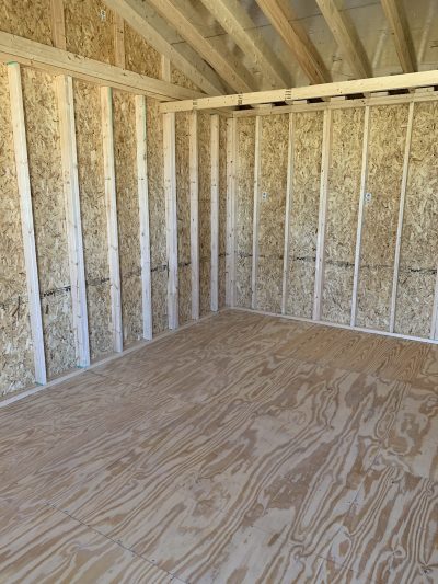 A room with plywood walls and wood flooring, perfect for a 12x24 Cottage Shed near me.