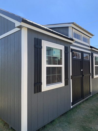 A 10x20 Chalet Shed with black shutters and windows for sale.