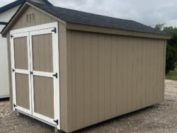 An 8x12 Basic Shed for sale sitting on a gravel lot.