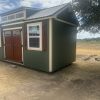 A 10x20 Chalet Shed in a field with a wooden door, available for sheds on sale.