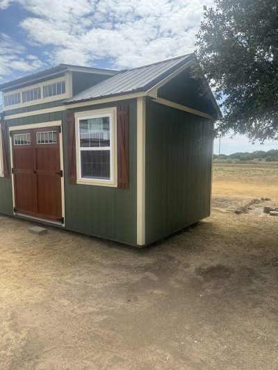 A 10x20 Chalet Shed in a field with a wooden door, available for sheds on sale.