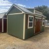 Two 10x20 Chalet Sheds on sale, one green and one brown, located in a field.