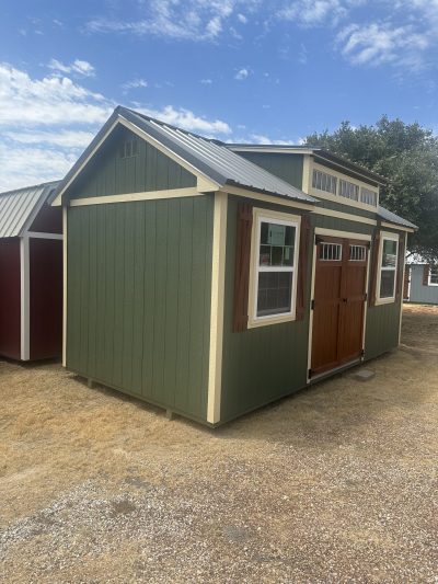 Two 10x20 Chalet Sheds on sale, one green and one brown, located in a field.
