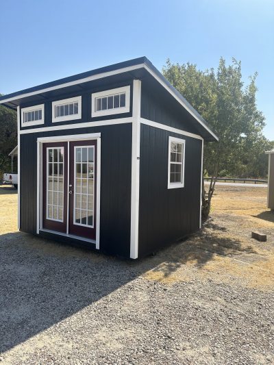 A 10x12 Studio Shed with a white door and windows, perfect for those looking for sheds on sale or a shed store near me.