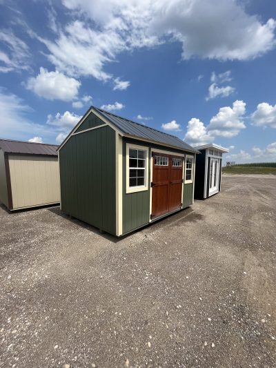 Two 10x14 Garden Sheds for sale in a parking lot.