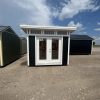 For sale: Two black and white 8x10 Studio Sheds in a parking lot.