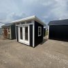 For sale: Two black 8x10 Studio Sheds in a parking lot.