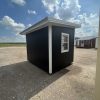 An 8x10 Studio Shed for sale, sitting on a gravel lot.