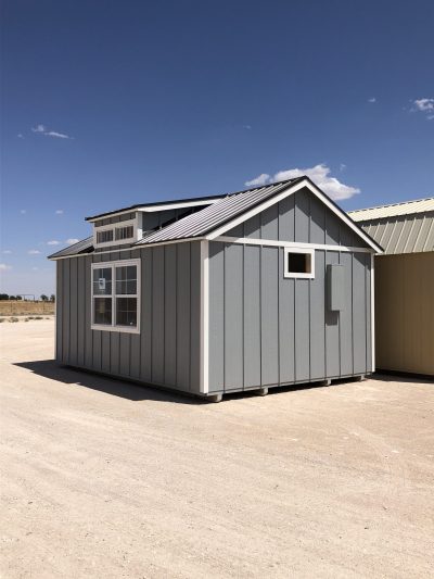 Two 14x20 Diamond Chalet Sheds sitting in a field next to each other, available for sale.