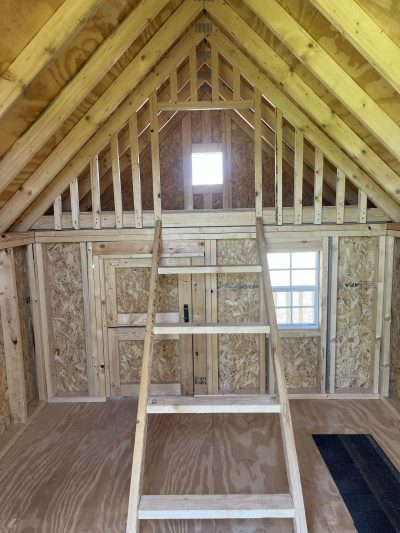 The inside of an 8x12 Hideout Playhouse Shed with a ladder and stairs, perfect for storing tools and equipment or converting into an additional living space.
