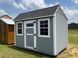 Two 8x12 Garden Sheds for sale in a field next to each other.