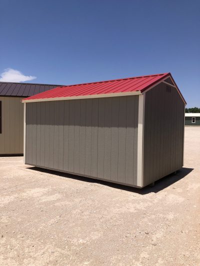 A 10x14 Utility Shed for sale with a red roof sitting on a dirt lot.
