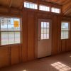 A rustic room adorned with wood walls and large windows, offering a serene ambiance, like the 12x20 Chalet Shed.