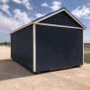 A 12x20 Chalet Shed for sale, colored in blue and white, sitting on a gravel lot.