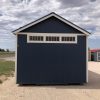 A 12x20 Chalet Shed for sale sitting on a gravel lot.