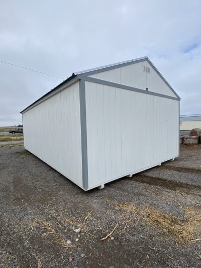 A 16x28 Garage Style Shed for sale sitting on a gravel lot.