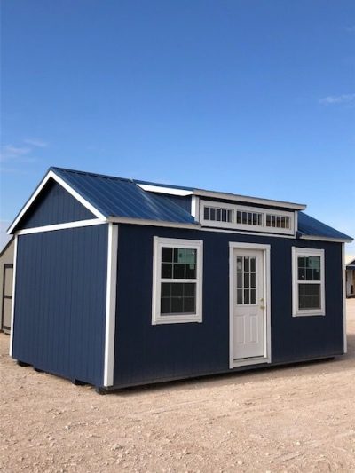 A 12x20 Chalet Shed with a white roof, available for sale, sitting on a dirt lot.