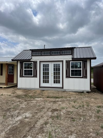 For sale 12x20 Chalet Shed: A white and brown shed sitting on a dirt lot.
