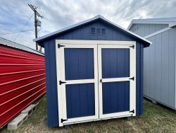A shed store near me, selling 8x8 Basic Sheds on sale, has a blue and white 8x8 Basic Shed sitting on a grassy area.