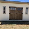 An 8x16 Studio Shed with a wooden door, available for sale at a nearby shed store.