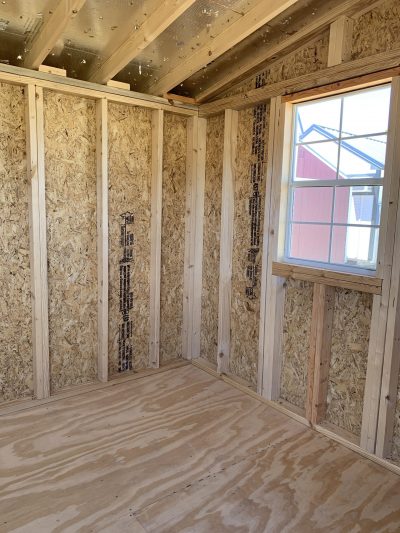 A room with wooden walls and a window, perfect as an 8x16 Studio Shed or storage space.