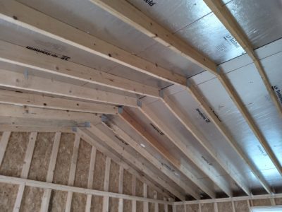 The ceiling of a house is being built with wood beams bought from a nearby store that has 16x30 Cottage Sheds on sale.
