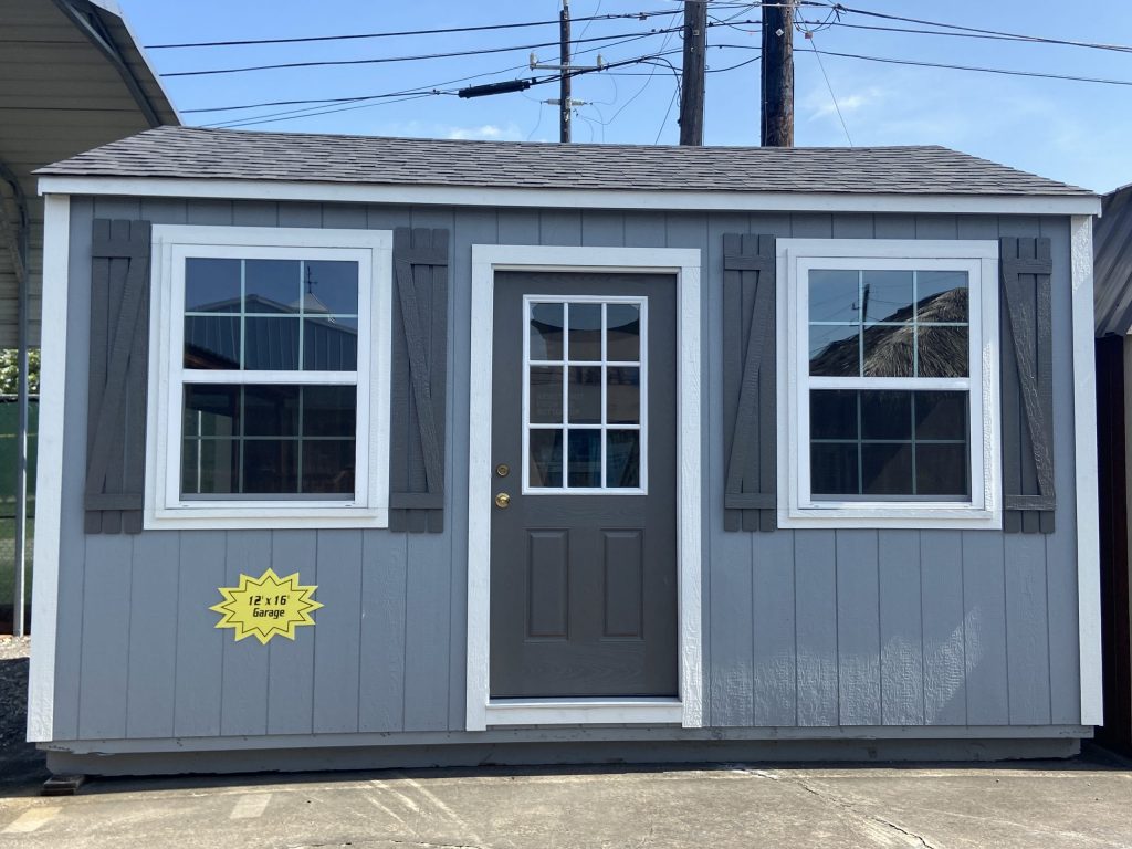  -  - A 12x16 Garage Shed with white shutters and a door for sale.