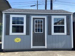 A 12x16 Garage Shed with white shutters and a door for sale.