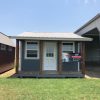 An affordable 14x28 Cottage Shed on sale near me, conveniently located in a field with a prominent sign.