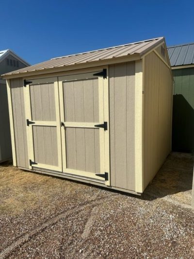 For sale: 10x10 Utility Shed, a tan shed sitting on a gravel lot.