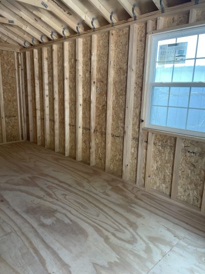 A room with wood flooring and a window, suitable for a 10x24 Cabinette Shed or store.