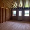 A vacant 14x28 Cottage Shed with wooden walls and a door that can be used as a shed for sale.