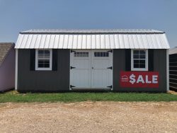 A gray shed with a sale sign advertising the 12x24 Lofted Barn on sale.