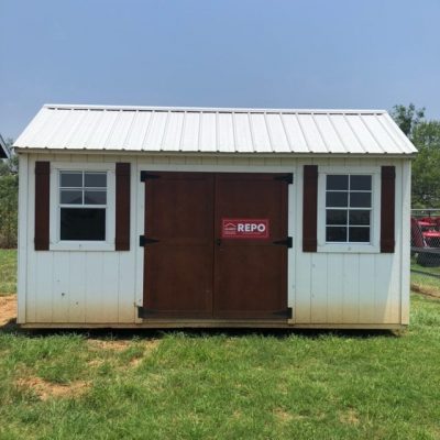 A 10x16 Garden Shed with a red door for sale in the middle of a grassy field.